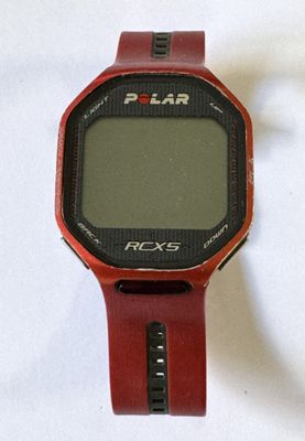 un gros plan d'une montre rouge posée sur une surface blanche