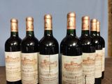 six bottles of red wine are lined up on a table