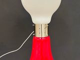 une image représentant une lampe rouge et blanche posée sur une surface noire
