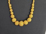 un collier composé de perles jaunes sur un mannequin noir