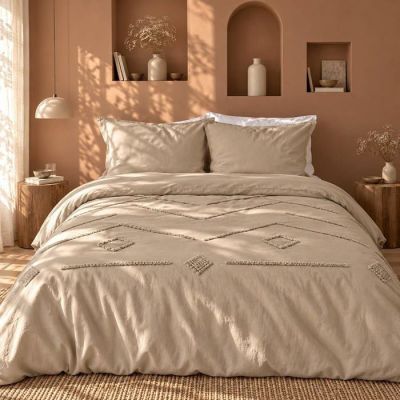 Le lit est fait avec une couette et des oreillers beiges.