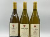 trois bouteilles de vin sont alignées sur une surface blanche