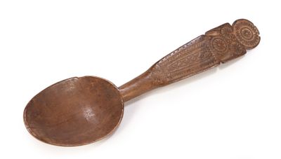 an old wooden spoon with a carved handle on a white surface