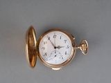 une montre de poche en or posée sur une surface grise