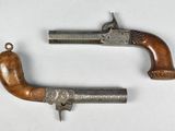 deux vieux pistolets à crosse en bois posés sur une surface blanche