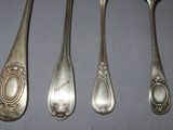 four silver spoons and a spoon with a picture of a lady on it