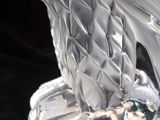 a clear glass sculpture of a bird sitting on a rock