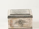 an antique silver plated box with a floral design on the lid