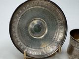 a silver plate and a silver cup sitting on a table