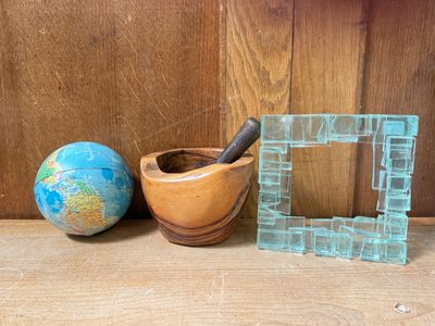 a glass picture frame next to a wooden bowl and a globe