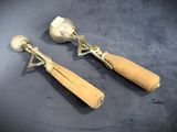 two silver spoons and a wooden spoon on a table
