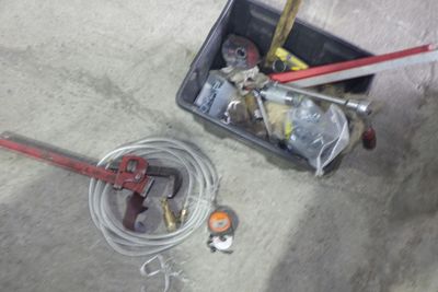 une caisse contenant des outils et un tuyau d'arrosage posée par terre
