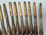 six antique silverplated flatware knives and spoons on a white surface
