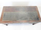 an old wooden coffee table with a glass top sitting on top of a white floor