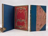 three books are open on a white surface, one is red and the other is blue