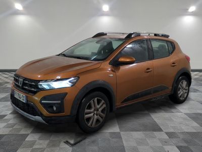 Une voiture marron est garée dans une pièce au sol à carreaux.