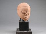 sculpture of a woman ' s head with closed eyes on a black base