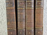 four old books are stacked on top of each other on a table