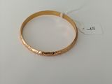 a close up of a gold bracelet on a white surface