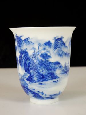 a blue and white cup with a mountain scene on it