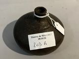 un vase noir muni d'une étiquette, posé sur une table