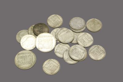 some silver coins on a gray surface with a coin in the foreground