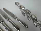 a lot of silver spoons and knives on the table