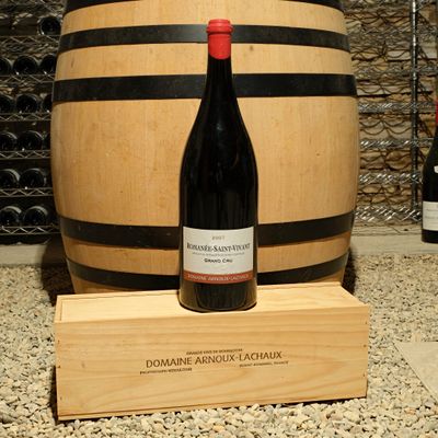 a bottle of wine sitting next to a barrel of wine