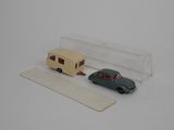 une petite voiture et une remorque miniatures posées sur une surface blanche
