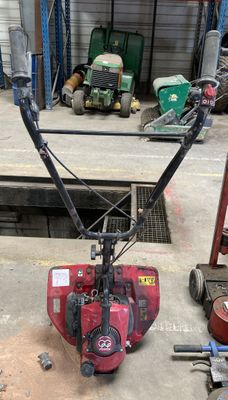 a red snow blower sitting on the ground in a garage