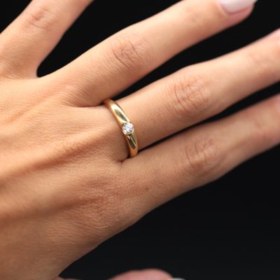 the woman is wearing a gold ring with a diamond on her finger