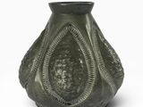 un vase vert posé sur une surface blanche
