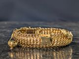 gold chain bracelet with a cross on it sitting on a table