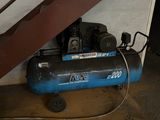 a blue air compressor sitting on the floor next to the stairs