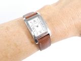 a person wearing a watch on their wrist on a white surface