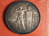 a close up of a coin on a red book with a picture of a woman holding a sword