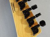 a close up of a wooden guitar neck with six black knobs