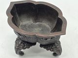 a small metal bowl on a stand on a white surface