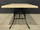 a wooden table with a metal base on a concrete floor