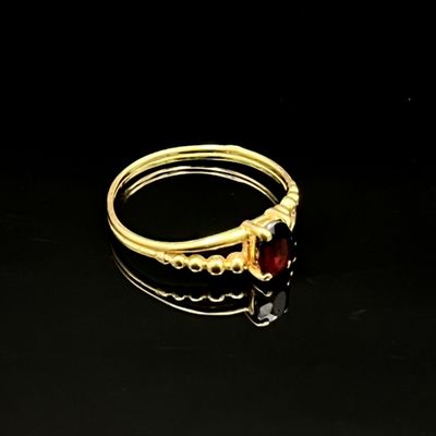 gros plan d'une bague en or avec une pierre rouge