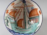 un petit bol orné d'un bateau, posé sur une table