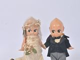 des figurines représentant la mariée et le marié, debout l'une à côté de l'autre sur une surface blanche