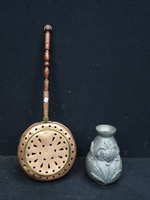 un petit vase en argent à côté d'une passoire en métal