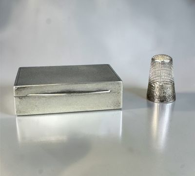 a small silver thimble next to a small silver thimble