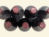 six bottles of wine are arranged in a row on a white surface