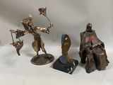 three bronze figurines of a man and a woman on a rock