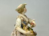 a figurine of a woman holding a basket of flowers