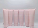four tubes of pink lotion sitting next to each other on a white surface