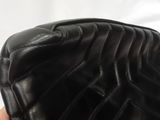 a hand holding a black purse that is on a white surface