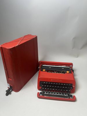une machine à écrire rouge posée à côté d'une mallette rouge